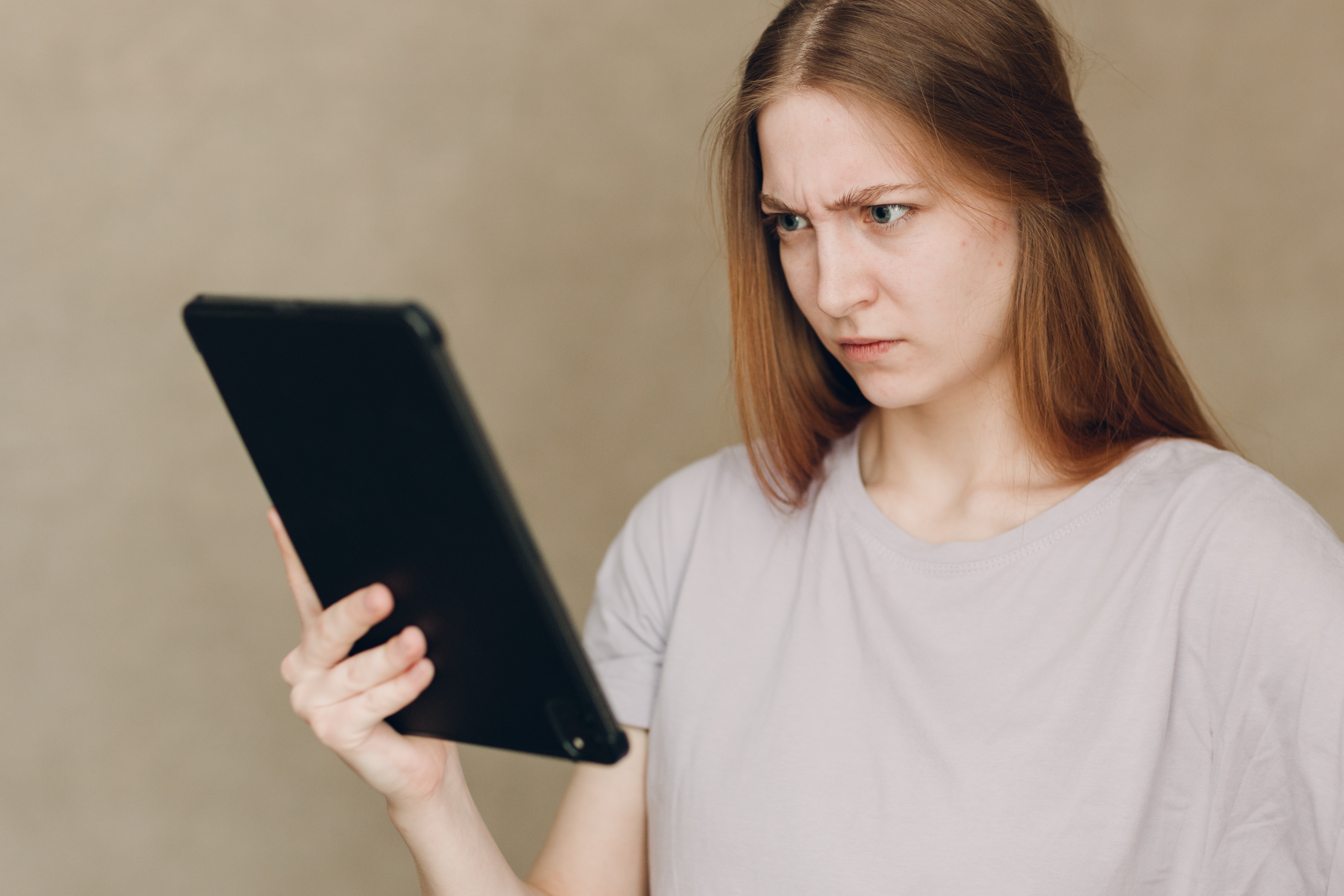 Student looks confused as she looks at tablet screen